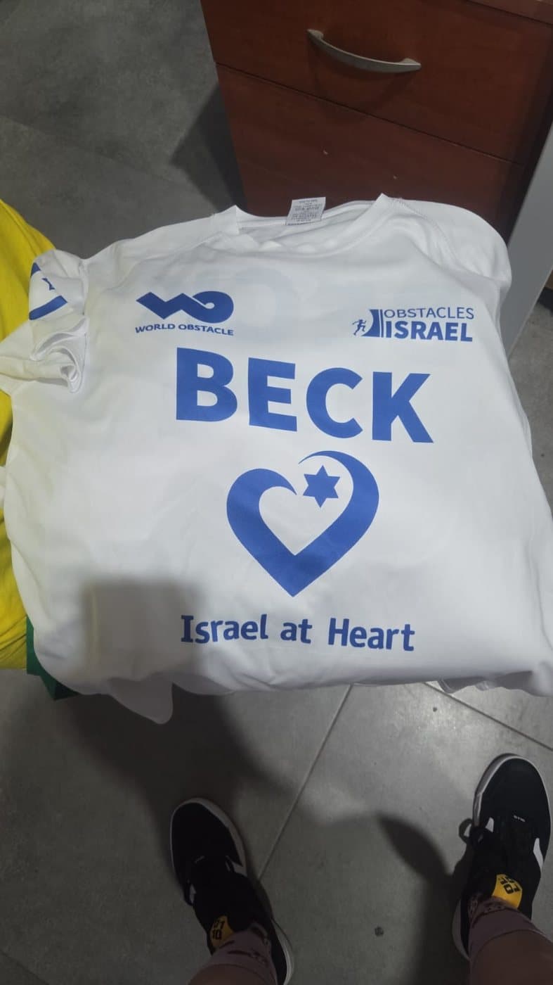 Nevo Beck’s white competition shirt, printed with his name, the World Obstacle and Obstacles Israel marks, and the Israel at Heart logo.