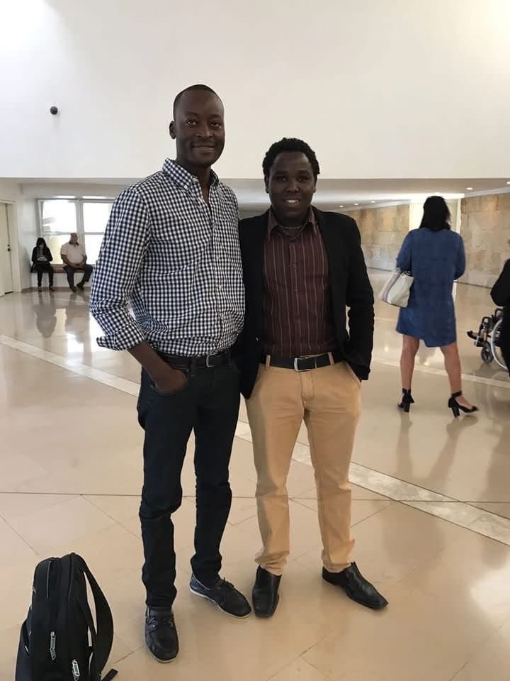 Two members of the African refugee community standing together in a hall in Israel.