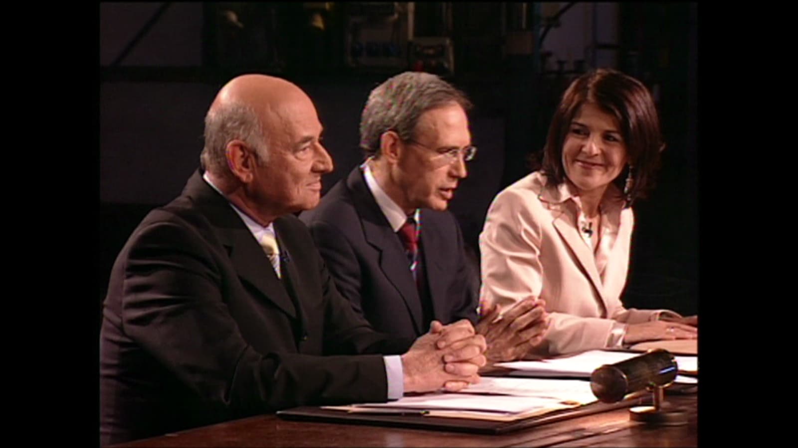 Three judges of The Ambassador seated behind their table on the show's set.